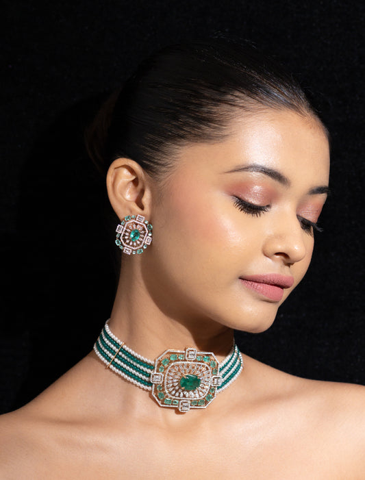 Woman wearing a green and gold necklace and earrings against a black background
