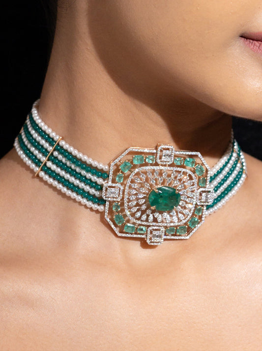 Woman wearing a green and gold necklace and earrings against a black background