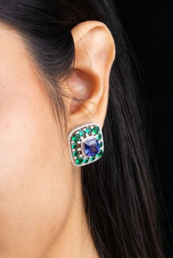 Woman wearing a necklace and earrings with gemstones on a dark background