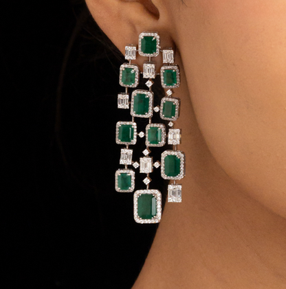 Woman wearing a green emerald necklace and earrings on a black background